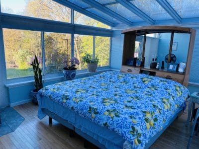 A bed with blue sheets and pillows in front of a window.