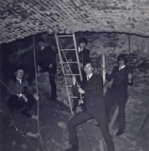 A group of men in suits and ties standing inside an underground cave.