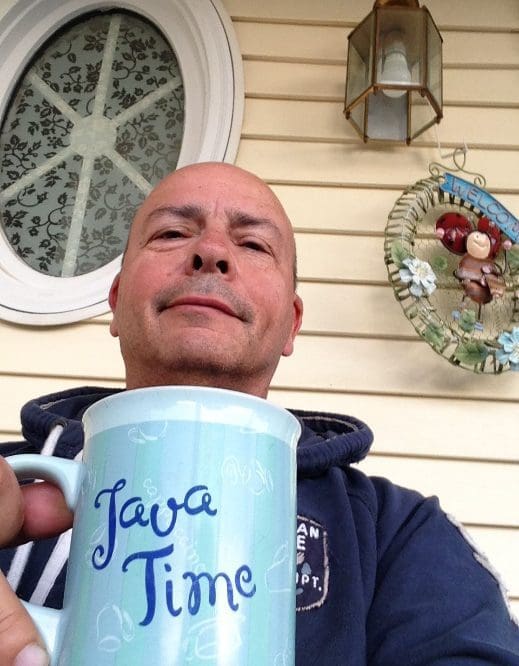 A man holding up a coffee mug with the words java time written on it.