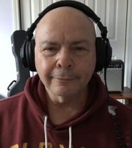 A man with headphones on wearing a red hoodie.