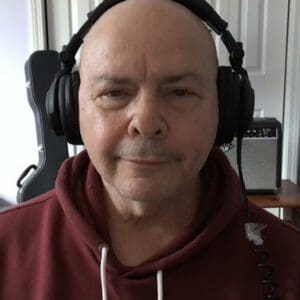 A bald man wearing headphones and looking at the camera.