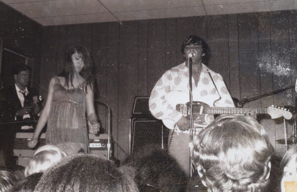A man and woman are playing guitar in front of an audience.
