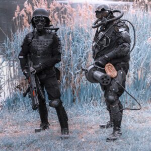 Two people in black suits and helmets standing next to each other.